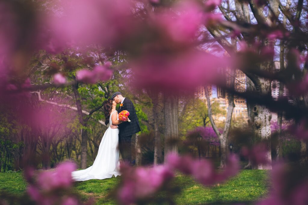 Couple getting married and kissing at a spring NYC elopement under cherry blossom tress