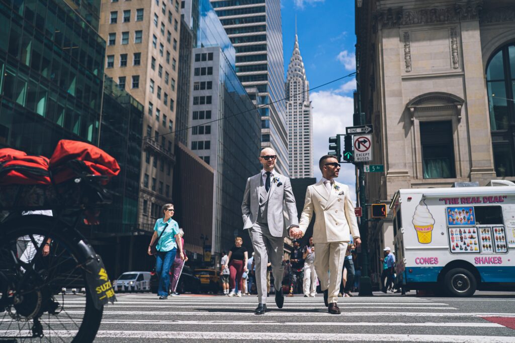 Candid moment of two grooms walking in cross walk in Manhattan, officiated by Jackie Reinking